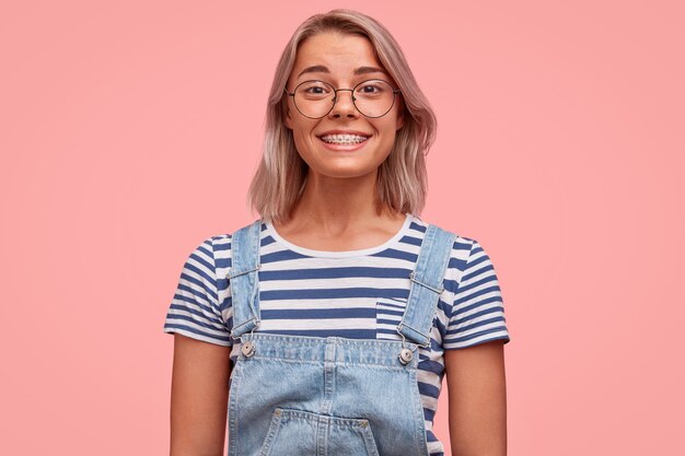 Porträt der jungen Frau mit gefärbtem Haar, das Overalls trägt