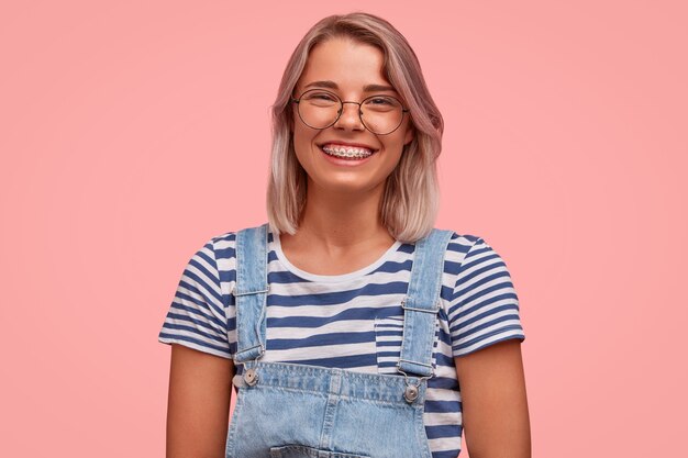 Porträt der jungen Frau mit gefärbtem Haar, das Overalls trägt