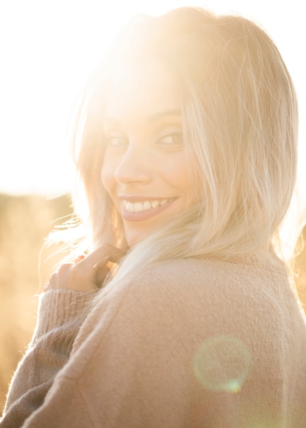 Porträt der jungen lächelnden Frau im Sonnenlicht, die Kamera betrachtet