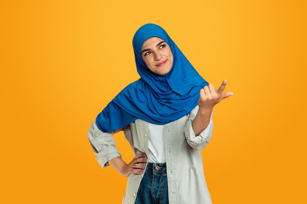 Porträt der jungen muslimischen Frau lokalisiert auf gelbem Studiohintergrund