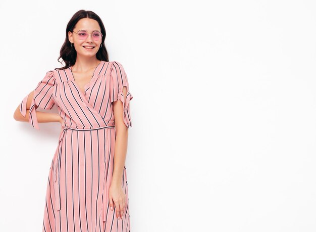 Porträt der jungen schönen lächelnden Frau im trendigen rosa Sommerkleid Sexy sorglose Frau, die im Studio posiert Positives Modell, das sich drinnen amüsiert Fröhlich und glücklich