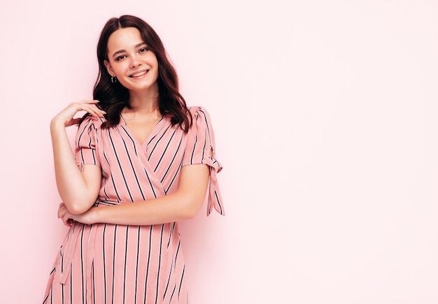 Porträt der jungen schönen lächelnden Frau im trendigen rosa Sommerkleid Sexy sorglose Frau posiert in der Nähe der Wand im Studio Positives Modell, das sich drinnen amüsiert Fröhlich und glücklich