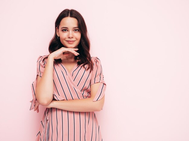 Porträt der jungen schönen lächelnden Frau im trendigen rosa Sommerkleid Sexy sorglose Frau posiert in der Nähe der Wand im Studio Positives Modell, das sich drinnen amüsiert Fröhlich und glücklich