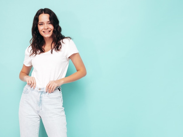 Porträt der jungen schönen lächelnden Frau in trendiger Sommerkleidung Sexy sorglose Frau posiert in der Nähe der blauen Wand im Studio Positives Modell, das sich drinnen amüsiert Fröhlich und glücklich