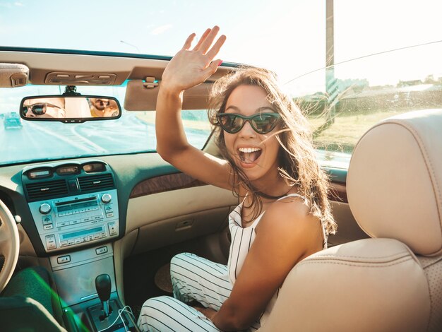 Porträt der jungen schönen und lächelnden Hippie-Frau und ihres Freundes im Cabrio