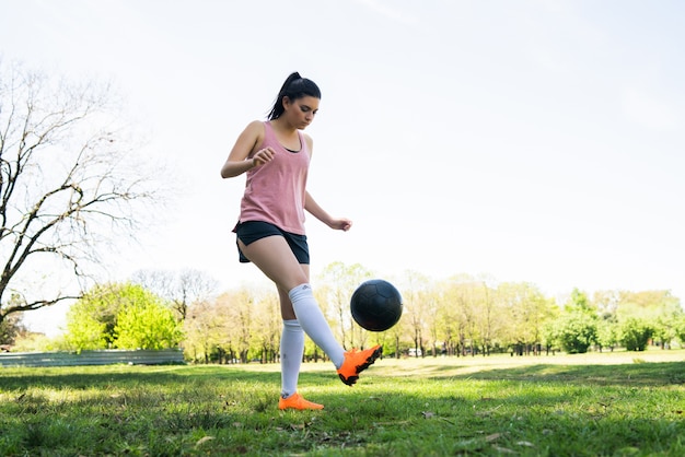 Porträt der jungen weiblichen Fußballspielerin, die Fähigkeiten auf dem Fußballplatz trainiert und übt