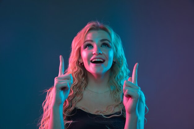 Porträt der kaukasischen jungen Frau auf Gradientenraum im Neonlicht