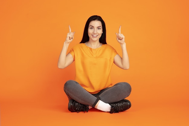 Porträt der kaukasischen jungen Frau auf orange Raum. Schönes weibliches brünettes Modell im Hemd
