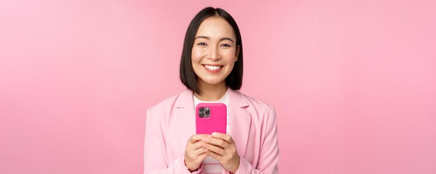 Porträt der lächelnden asiatischen Unternehmensperson der Geschäftsfrau, die Smartphone-Handyanwendung verwendet