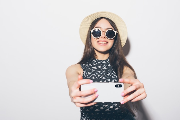 Porträt der lächelnden attraktiven Frau im Hut stehend und ein Selfie isoliert