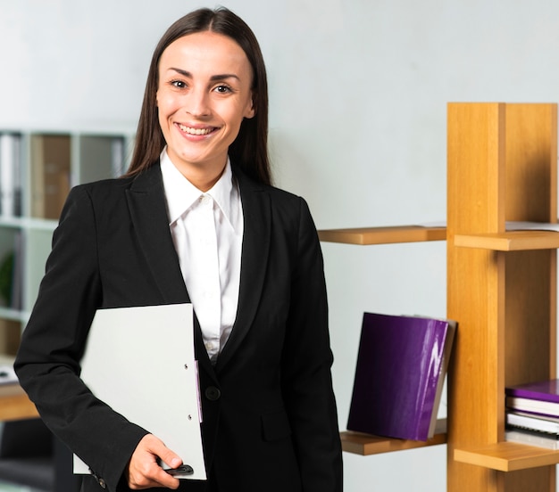 Porträt der lächelnden jungen Geschäftsfrau, die im Büro steht