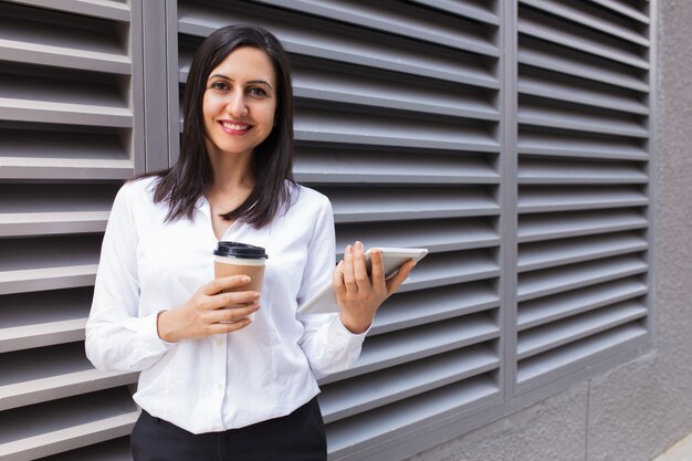 Porträt der lächelnden jungen Geschäftsfrau mit Kaffee und Berührungsfläche