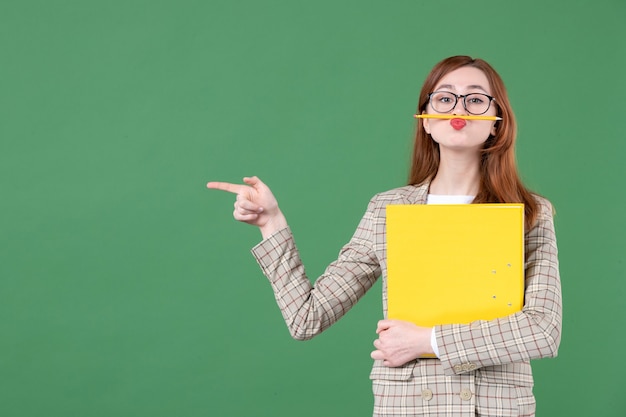 Porträt der Lehrerin, die gelbe Datei auf Grün hält