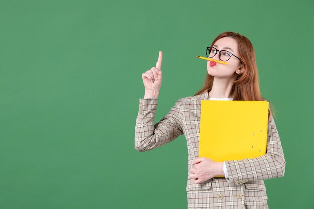 Porträt der Lehrerin mit Akte und Bleistift um den Mund auf Grün