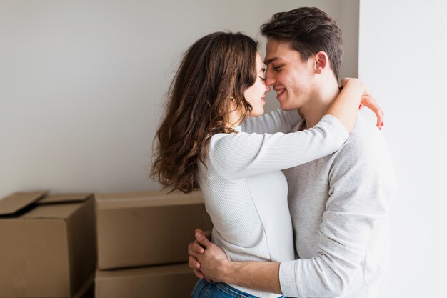 Porträt der liebevollen jungen Paare, die Stellung vor Pappschachteln umfassen