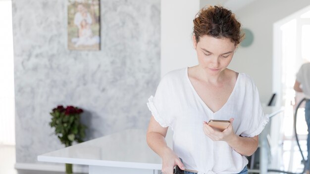 Kostenloses Foto porträt der mutter, die ihr handy überprüft