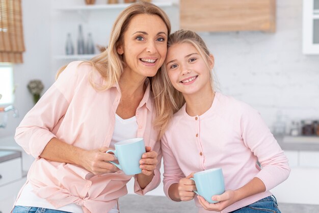 Porträt der Mutter und der Tochter, die Becher halten