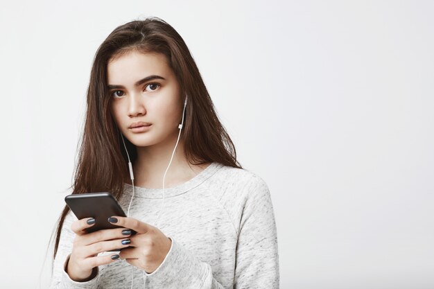 Porträt der niedlichen attraktiven kaukasischen Frau, die Musik und Nachrichten mit lässigem Ausdruck hört.