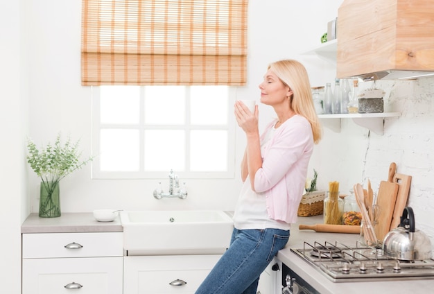 Porträt der reizenden älteren Frau, die zu Hause Kaffee genießt