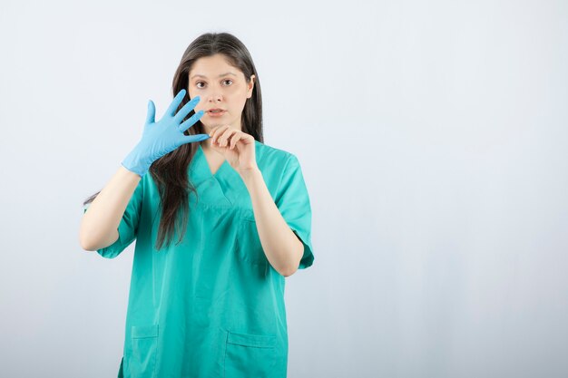 Porträt der Ärztin, die medizinische Handschuhe auszieht.