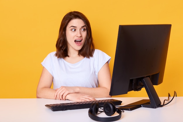 Porträt der schockierten Frau, die vor dem Computer sitzt