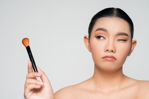 Porträt der schönen asiatischen Frau mit Make-up Rougepinsel