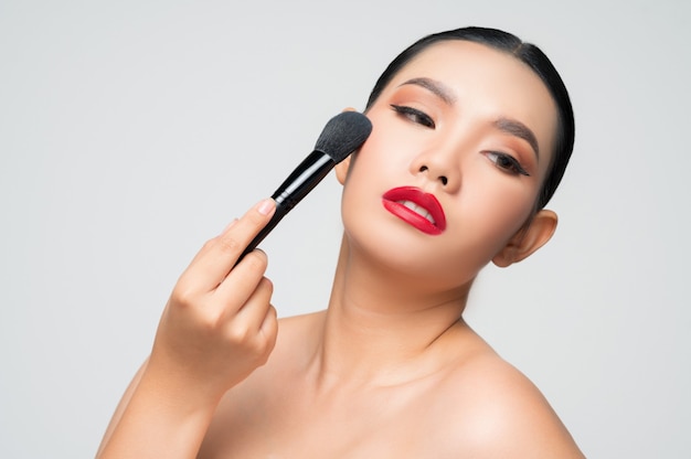 Porträt der schönen asiatischen Frau mit Make-up Rougepinsel
