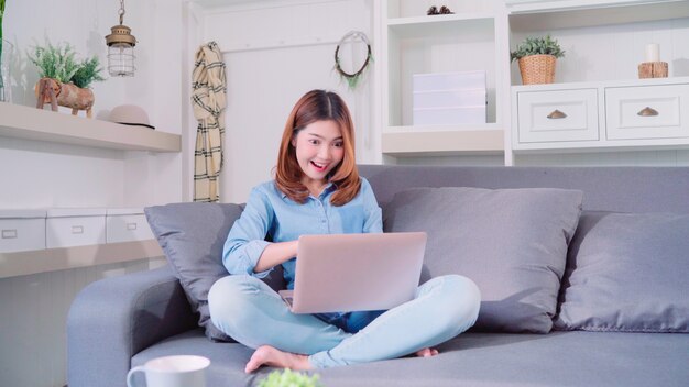 Porträt der schönen attraktiven jungen lächelnden Asiatin, die Computer oder Laptop verwendet