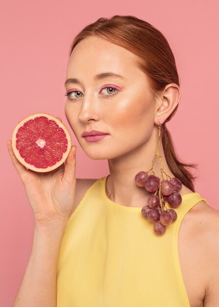 Porträt der schönen Frau, die eine Frucht hält