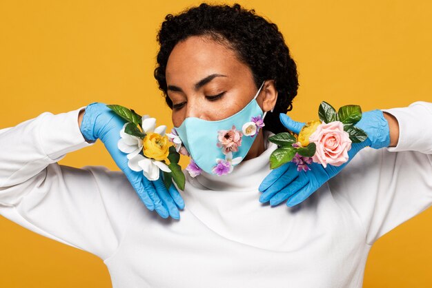 Porträt der schönen Frau mit Blumenmaske und Handschuhen