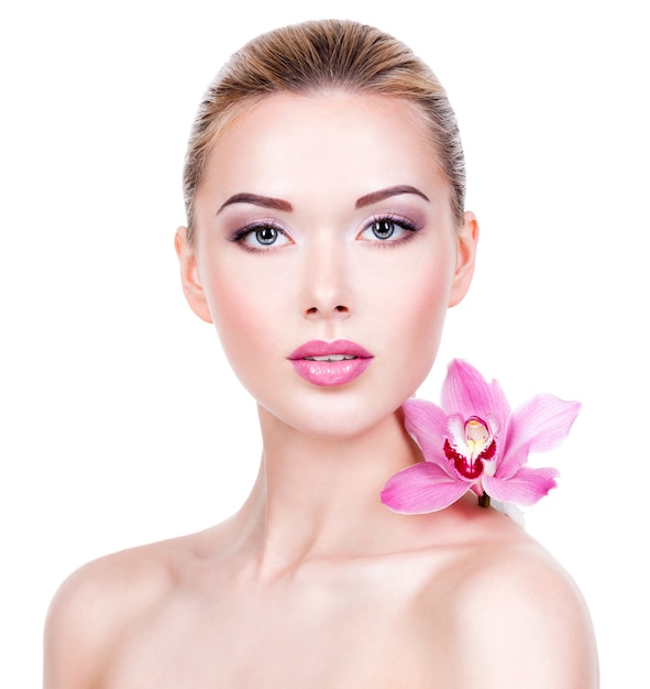 Porträt der schönen Frau mit den rosa Blumen. Hübsches erwachsenes Mädchen mit gesunder Haut eines Gesichts. - isoliert auf weißem Hintergrund