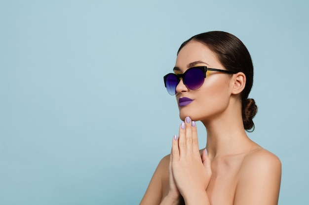 Porträt der schönen Frau mit hellem Make-up und Sonnenbrille. Stilvolle, modische Marke und Frisur. Farben des Sommers. Ernst, zuversichtlich.