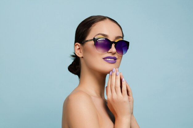 Porträt der schönen Frau mit hellem Make-up und Sonnenbrille. Stilvolle, modische Marke und Frisur. Farben des Sommers. Ernst, zuversichtlich.