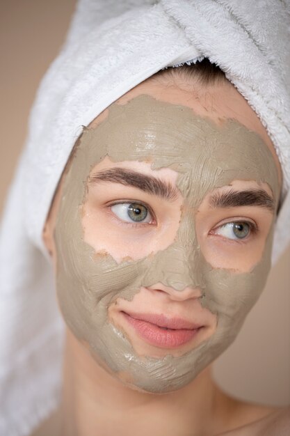 Porträt der schönen Frau mit Schönheitslehmmaske auf ihrem Gesicht