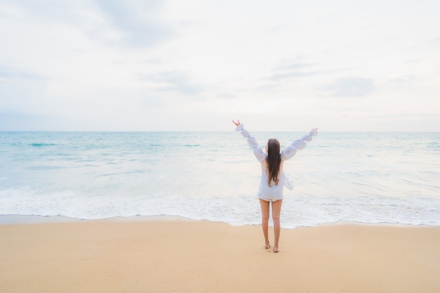 Porträt der schönen jungen asiatischen Frau, die sich um Strand im Freien im Reiseurlaub entspannt