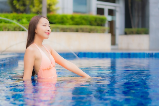 Porträt der schönen jungen asiatischen Frau entspannt auf dem Swimmingpool im Hotelresort