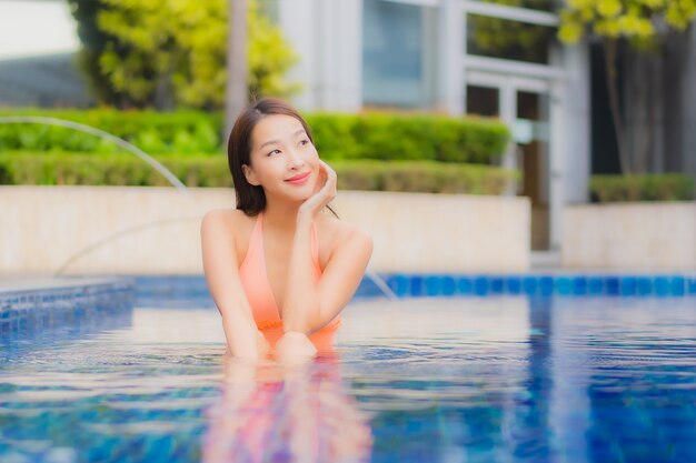 Porträt der schönen jungen asiatischen Frau entspannt auf dem Swimmingpool im Hotelresort