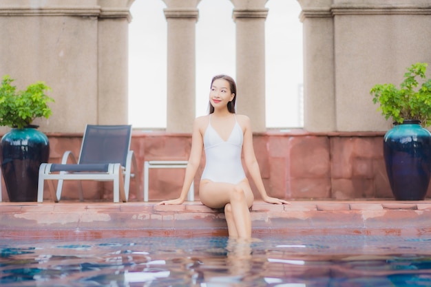 Porträt der schönen jungen asiatischen frau entspannt sich im pool
