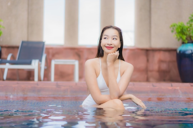 Porträt der schönen jungen asiatischen Frau entspannt sich im Pool