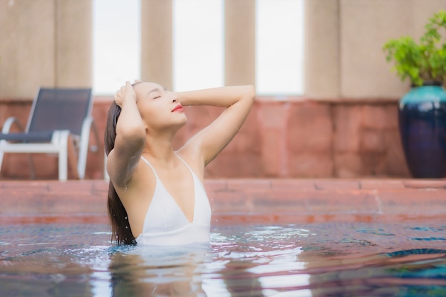 Porträt der schönen jungen asiatischen Frau entspannt sich im Pool