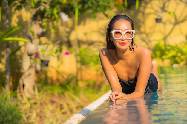 Porträt der schönen jungen asiatischen Frau entspannt sich im Schwimmbad