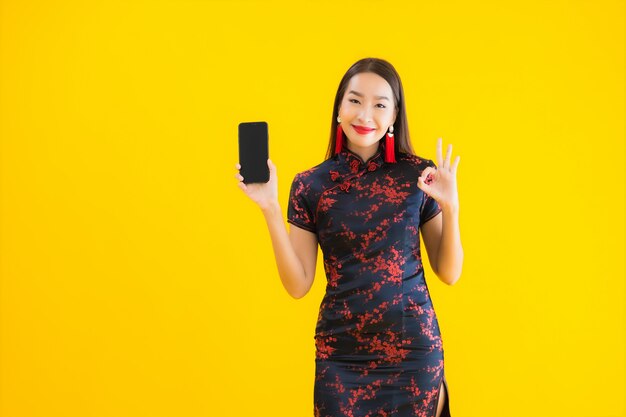 Porträt der schönen jungen asiatischen Frau trägt chinesisches Kleid und benutzt Smartphone