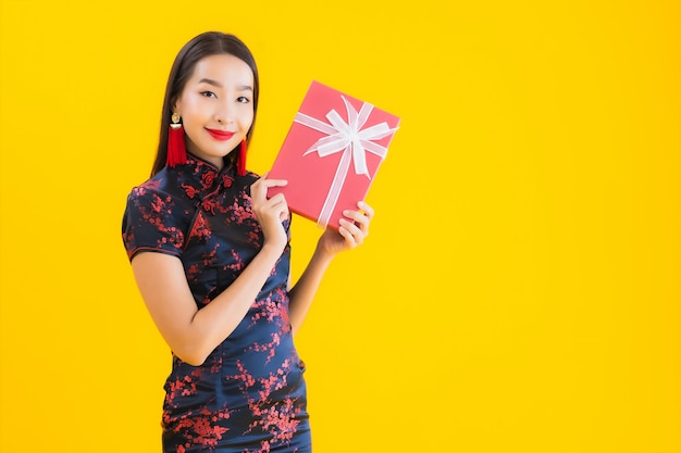 Porträt der schönen jungen asiatischen Frau trägt chinesisches Kleid und halten rote Geschenkbox