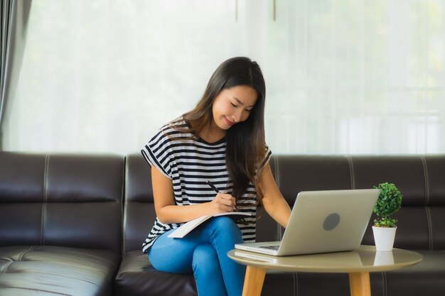 Porträt der schönen jungen asiatischen Frau unter Verwendung des Laptops