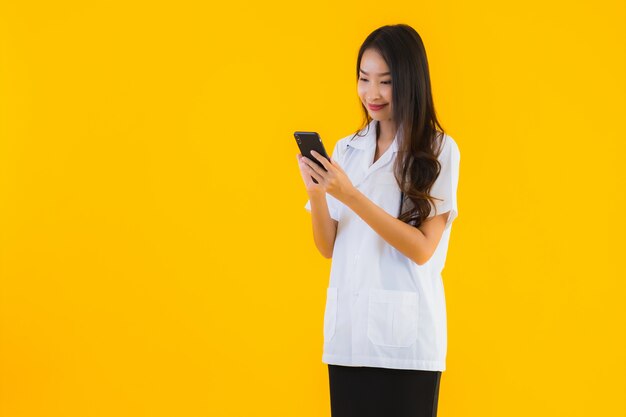 Porträt der schönen jungen asiatischen Ärztin benutzt Smartphone