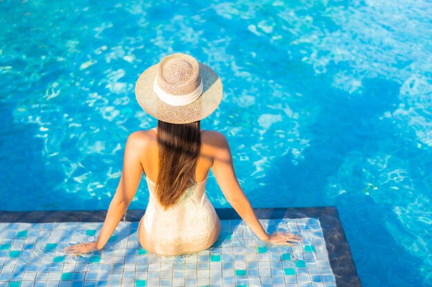 Porträt der schönen jungen Frau, die am Schwimmbad entspannt