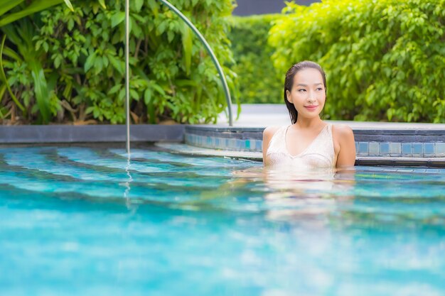 Porträt der schönen jungen Frau, die am Schwimmbad entspannt