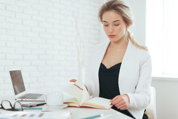 Porträt der schönen jungen Frau, die im Büro arbeitet