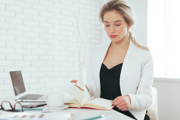 Porträt der schönen jungen Frau, die im Büro arbeitet