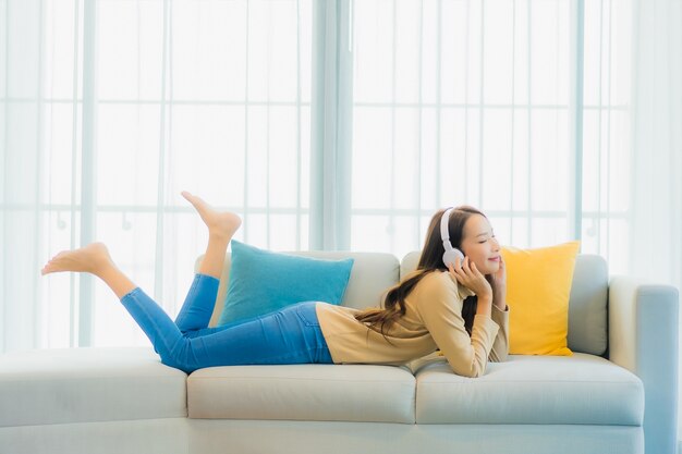 Porträt der schönen jungen Frau, die Musik auf Sofa im Wohnzimmer hört